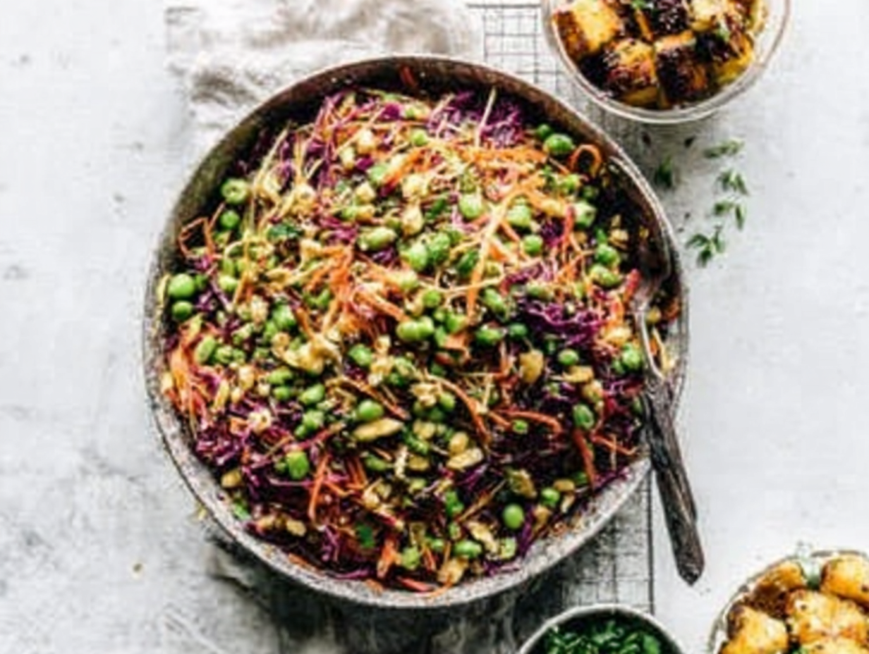 A large glass bowl filled with cashew crunch salad with sesame dressing, showing the vibrant colors of the cabbage, carrots, and cashews.